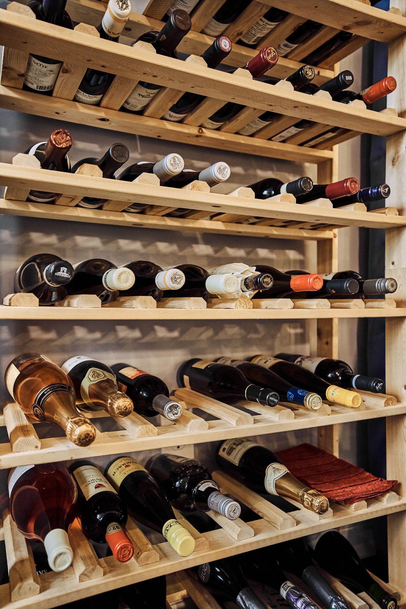 A wooden rack filled with bottles of red, white and rosé wine.