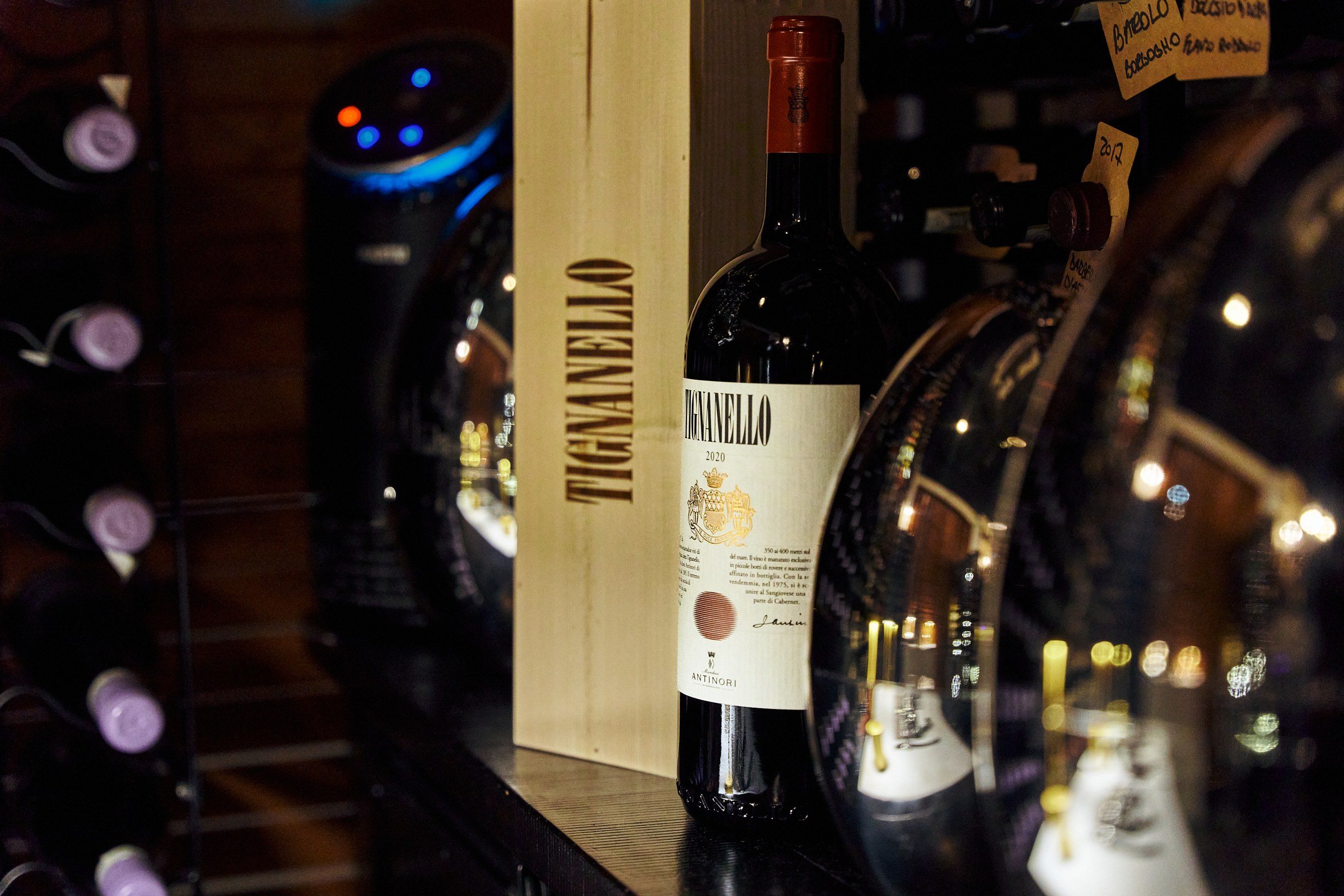 A bottle of Tignanello beside its wooden case, lit among the wine racks.