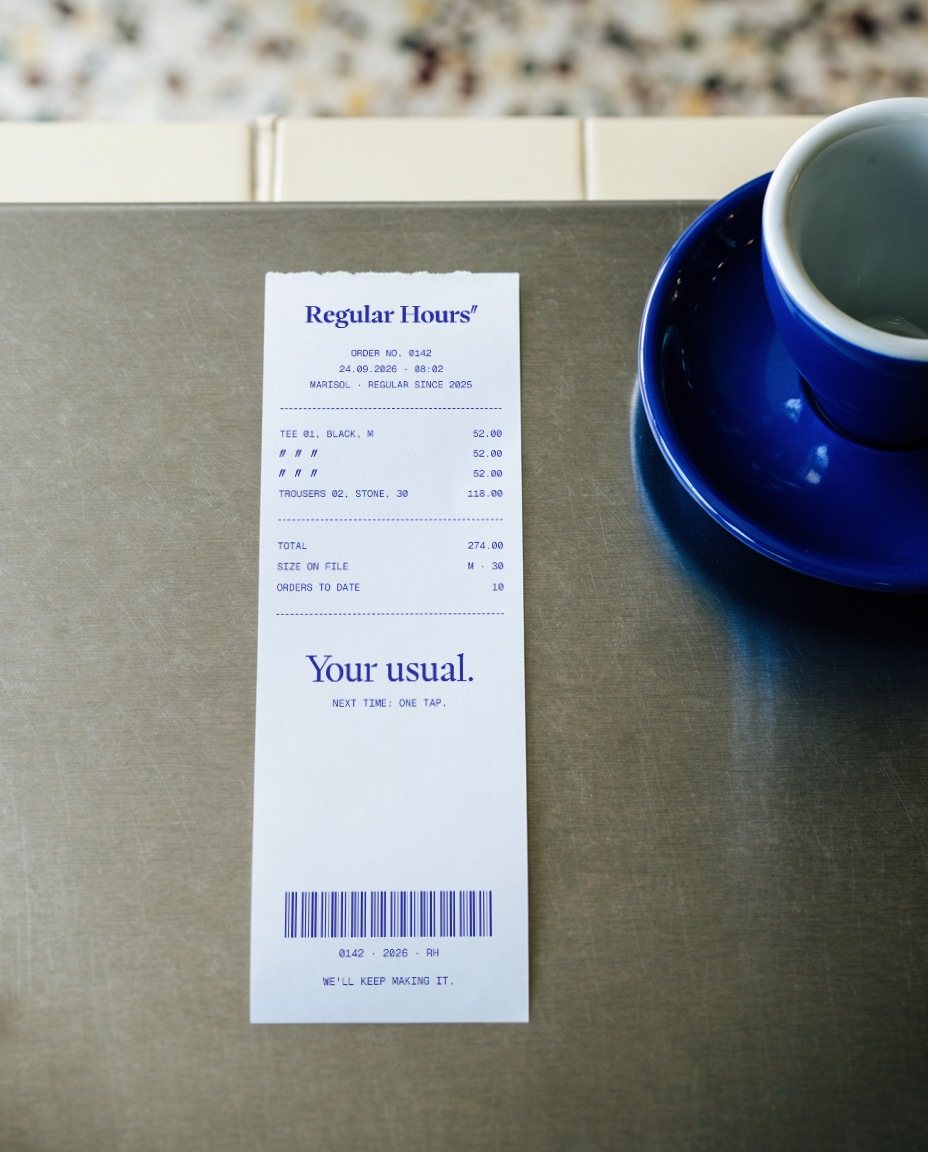 A carbon-blue receipt on a steel counter, repeated lines as dittos, beside a blue espresso cup