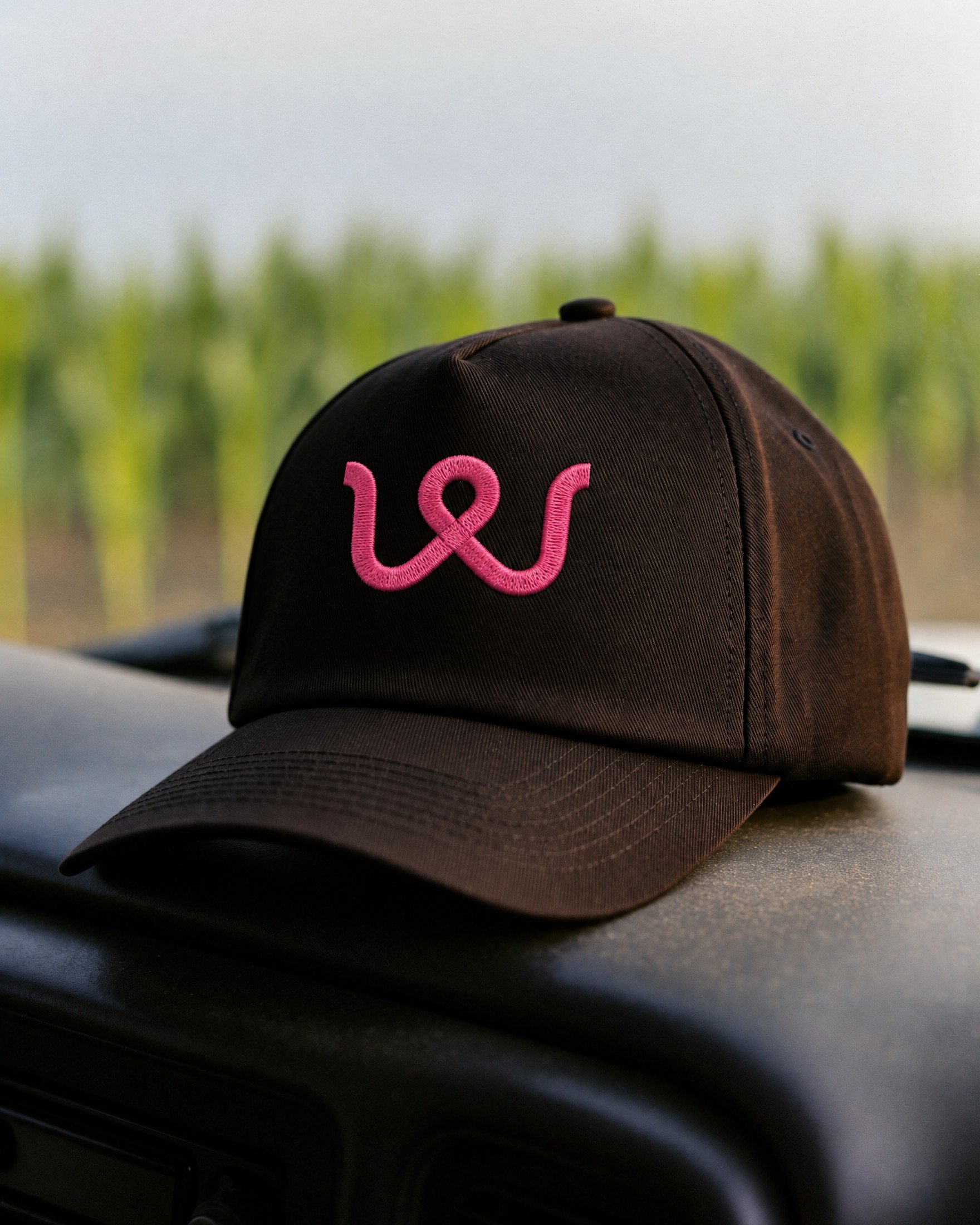 A black cap with the pink thread on a truck dashboard